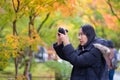 Young beautiful photographer with the professional camera taking photo beautiful autumn colourful maple leaf in Kyoto Japan Royalty Free Stock Photo