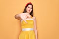 Young beautiful pin up woman wearing 50s fashion vintage dress over yellow background looking unhappy and angry showing rejection Royalty Free Stock Photo