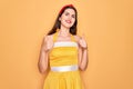 Young beautiful pin up woman wearing 50s fashion vintage dress over yellow background success sign doing positive gesture with Royalty Free Stock Photo