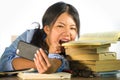 Young beautiful and playful Asian Korean student teenager taking selfie picture on desk with mobile phone biting pile of books in