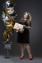 Young beautiful plus size model in black dres with gift box, xxl woman on gray studio background Royalty Free Stock Photo