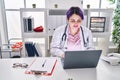 Young beautiful plus size woman doctor using laptop working at clinic Royalty Free Stock Photo