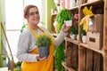 Young beautiful plus size woman florist smiling confident holding plants at flower shop Royalty Free Stock Photo