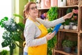 Young beautiful plus size woman florist using touchpad touching plant at flower shop Royalty Free Stock Photo