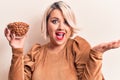 Young beautiful plus size woman holding bowl with healthy almonds over white background celebrating achievement with happy smile Royalty Free Stock Photo