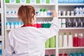 Young beautiful plus size woman pharmacist holding product on shelving at pharmacy Royalty Free Stock Photo