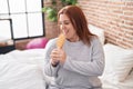 Young beautiful plus size woman singing song using brush as a microphone at bedroom Royalty Free Stock Photo