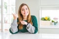 Young beautiful plus size woman wearing casual striped sweater Pointing to the back behind with hand and thumbs up, smiling Royalty Free Stock Photo