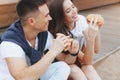 Young beautiful positive couple eating hambergers sitting on beach Royalty Free Stock Photo