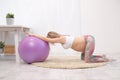 A young beautiful pregnant Caucasian woman sits on the soft carpet of the house. He is engaged in fitness and doing Royalty Free Stock Photo