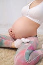 A young beautiful pregnant Caucasian woman sits on the soft carpet of the house. He is engaged in fitness and doing Royalty Free Stock Photo