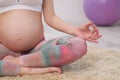 A young beautiful pregnant Caucasian woman sits on the soft carpet of the house. He is engaged in fitness and doing Royalty Free Stock Photo