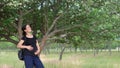 A young, beautiful, pregnant girl, near a tree, in a black T-shirt.