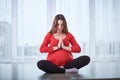 Young beautiful pregnant woman doing yoga asana Padmasana - lotus pose at home. Royalty Free Stock Photo