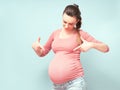 Young beautiful pregnant woman dreams over isolated blue background.