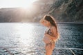 Pregnant woman with long hair in swimsuit on yacht
