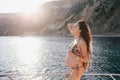 Pregnant woman with long hair in swimsuit on yacht