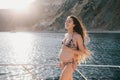 Pregnant woman with long hair in swimsuit on yacht