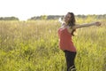 Young beautiful pregnant woman holding tummy smiling, in red a light summer dress, happy on meadow the grass Royalty Free Stock Photo