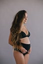 Pregnant woman with long curly hair in black underwear.