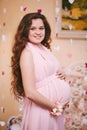 Young beautiful pregnant woman with long red hair in a delicate boudoir pink long dress. Fashion for pregnant women. Happy Royalty Free Stock Photo