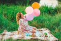 Young beautiful pregnant woman sitting at a picnic on a blanket in the park with colorful balloons in hands closeup Royalty Free Stock Photo