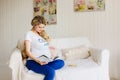 Young beautiful pregnant woman sitting on sofa with a book. Royalty Free Stock Photo
