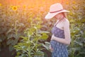 Young beautiful pregnant woman stands in a hat and dress on the field of sunny blooming sunflowers Royalty Free Stock Photo