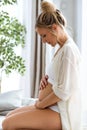 Young beautiful pregnant woman touching and looking her belly sitting on the sofa at home Royalty Free Stock Photo