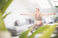 Young beautiful pregnant woman training pilates at home in her living room. Healthy lifestyle and active pregnancy and Royalty Free Stock Photo