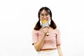 Young beautiful and pretty Asian female student holding a microphone singing with attractive smile isolated over white background. Royalty Free Stock Photo