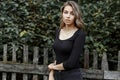 Young beautiful pretty cute rural woman in fashionable jeans in a stylish black t-shirt is standing near a wooden vintage fence Royalty Free Stock Photo