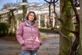 Young beautiful pretty tourist girl in warm hat and coat with backpack walking at cold autumn in Europe city enjoying Royalty Free Stock Photo