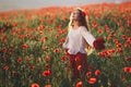 Young beautiful woman walking and dancing through a poppy field at sunset Royalty Free Stock Photo