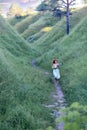 A young beautiful red-haired girl in a green sundress in the summer walks where the hills and mountains, green grass and