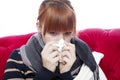 Young beautiful red haired girl on red sofa with hanky on nose i