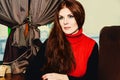 Young beautiful red-haired girl sitting at a table in a cafe smiling. Winter portrait Royalty Free Stock Photo