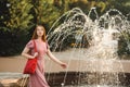 Young beautiful red-haired long-haired woman in a summer pink dress walks through the streets of a summer city. Royalty Free Stock Photo