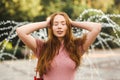 Young beautiful red-haired long-haired woman in a summer pink dress walks through the streets of a summer city. Royalty Free Stock Photo