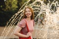 Young beautiful red-haired long-haired woman in a summer pink dress walks through the streets of a summer city. Royalty Free Stock Photo