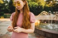 Young beautiful red-haired long-haired woman in a summer pink dress walks through the streets of a summer city. Royalty Free Stock Photo