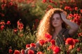 Young beautiful red-hear girl in red poppy field