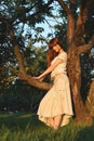Young beautiful redhaired woman in apple orchard
