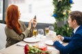 Redhaired beautiful woman with smartphone and man in restaurant