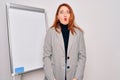 Young beautiful redhead businesswoman doing business presentation using magnetic board making fish face with lips, crazy and Royalty Free Stock Photo