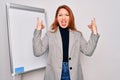 Young beautiful redhead businesswoman doing business presentation using magnetic board shouting with crazy expression doing rock