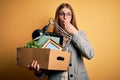 Young beautiful redhead businesswoman fired holding carboard box over yellow background cover mouth with hand shocked with shame