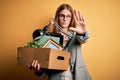 Young beautiful redhead businesswoman fired holding carboard box over yellow background with open hand doing stop sign with