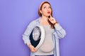 Young beautiful redhead pregnant woman expecting baby holding weighting machine serious face thinking about question, very Royalty Free Stock Photo