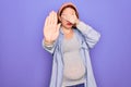 Young beautiful redhead pregnant woman expecting baby over isolated purple background covering eyes with hands and doing stop Royalty Free Stock Photo